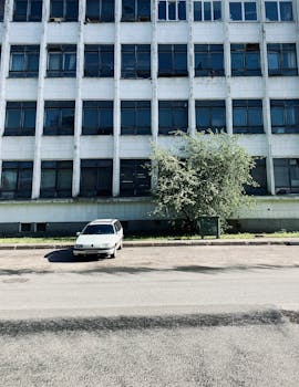 A parked white car in front of a tall building in Sankt-Peterburg, Russia.