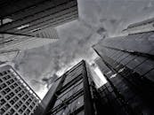 以灰度捕捉的现代摩天大楼在云层中的仰视画面