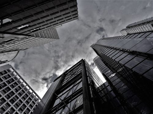 Free An upward view of modern skyscrapers against a cloudy sky, captured in grayscale. Stock Photo