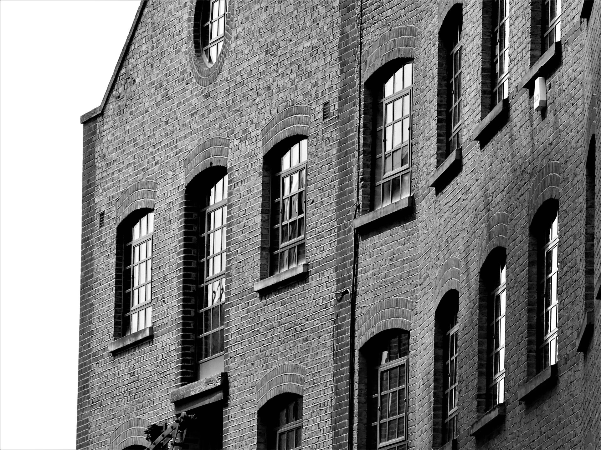 Black and white image of a historic brick building facade with arched windows, showcasing classic architecture.