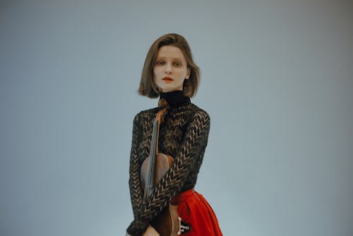 A Woman in Black Long Sleeve Shirt and Red Skirt Holding a Violin