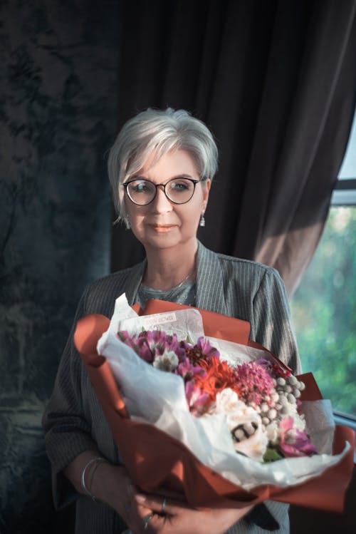 Free Portrait of an Elderly Woman Holding a Bouquet of Flowers Stock Photo