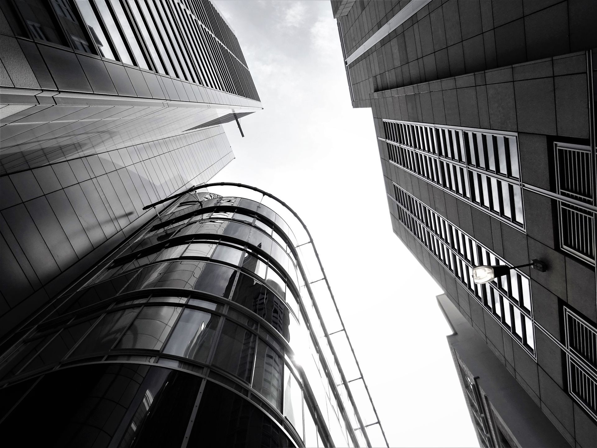 A low-angle view of modern skyscrapers with glass facades and steel structures in an urban setting.