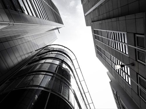 Free A low-angle view of modern skyscrapers with glass facades and steel structures in an urban setting. Stock Photo