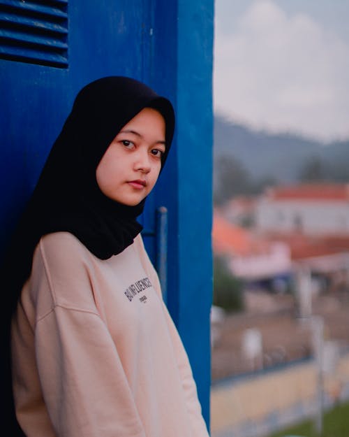 Free A Girl with a Black Hijab Leaning on a Blue Door Stock Photo