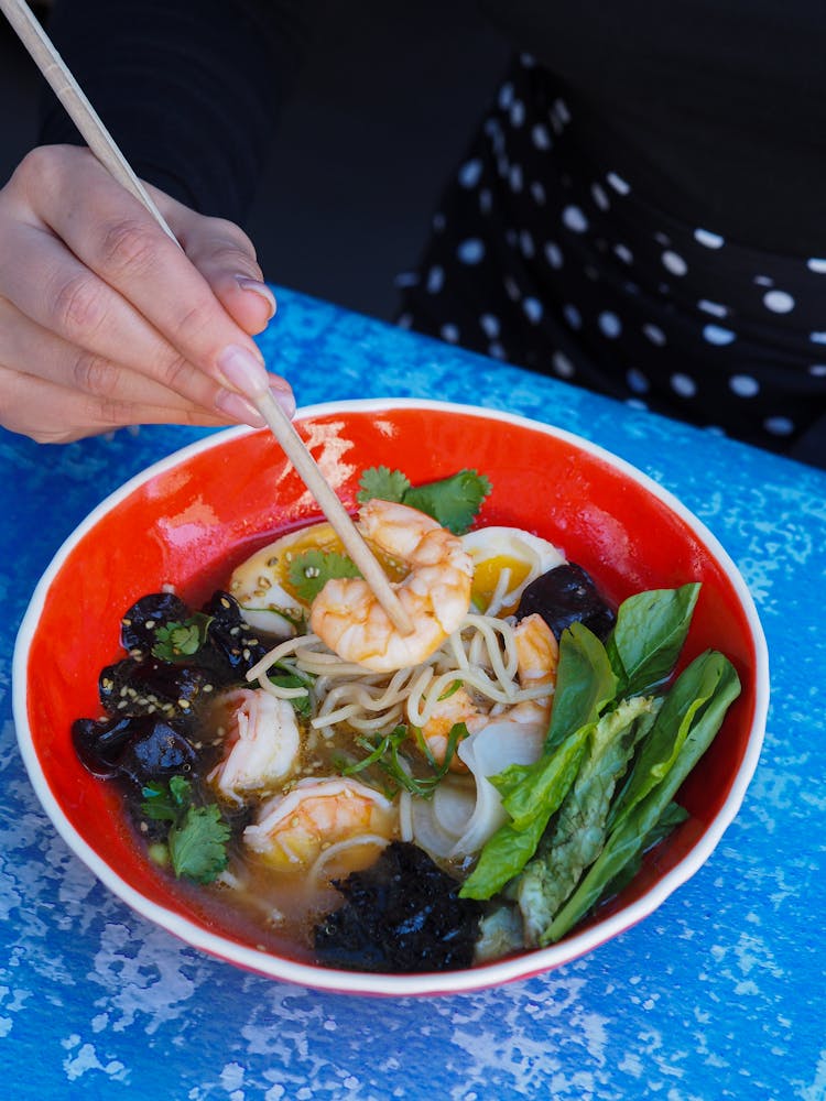 Person Eating A Bowl Of Noodles