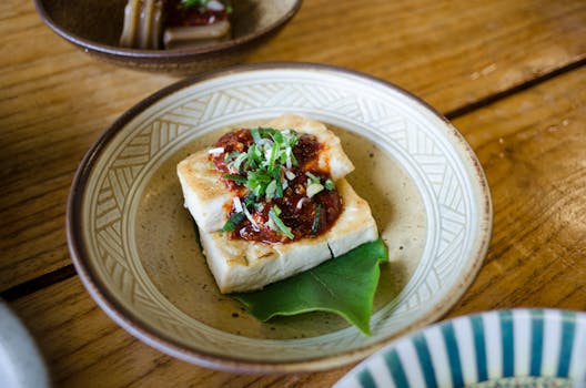 Close-up of delicious tofu dish topped with spicy sauce and herbs, perfect for healthy meals.