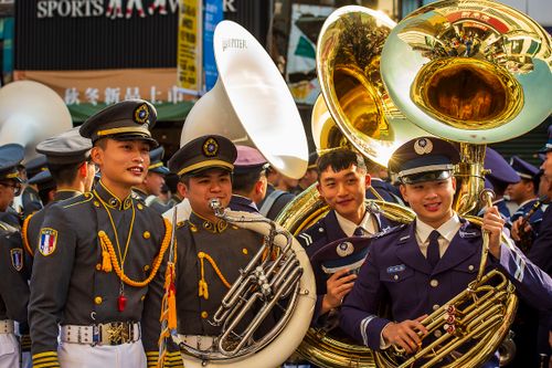 Free Smiling military band members in uniform playing brass instruments outdoors in Taiwan. Stock Photo