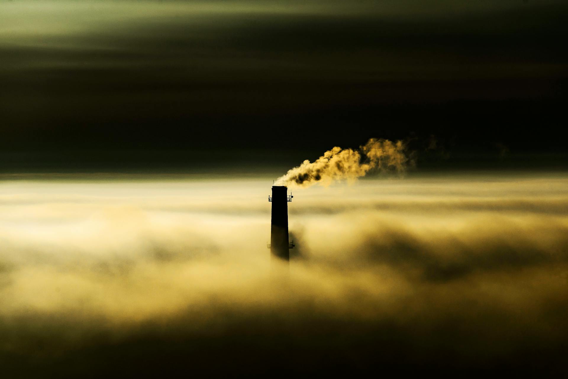 An Industrial Chimney Over a Thick Fog Emitting Smoke