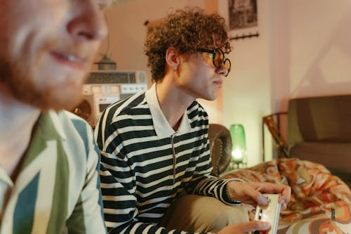 Photo of a Man with Curly Hair Playing a Video Game Console