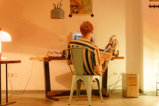 A man in a retro office setting using a computer, evoking 90s nostalgia.