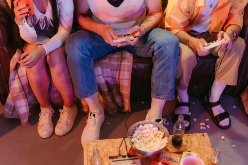 Free A group of teenagers enjoying a vintage gaming session indoors with snacks and drinks. Stock Photo
