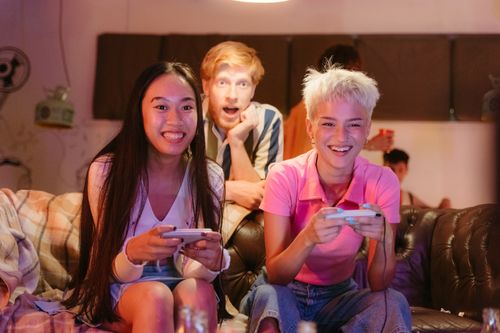 Free A group of diverse friends enjoying a gaming session indoors with smiles and laughter. Stock Photo