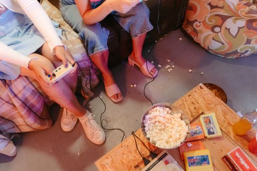 Two teenagers playing video games with snacks indoors, creating a fun and relaxed atmosphere.