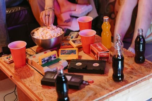 A nostalgic gaming setup with retro consoles, drinks, and snacks enjoying a cozy evening.