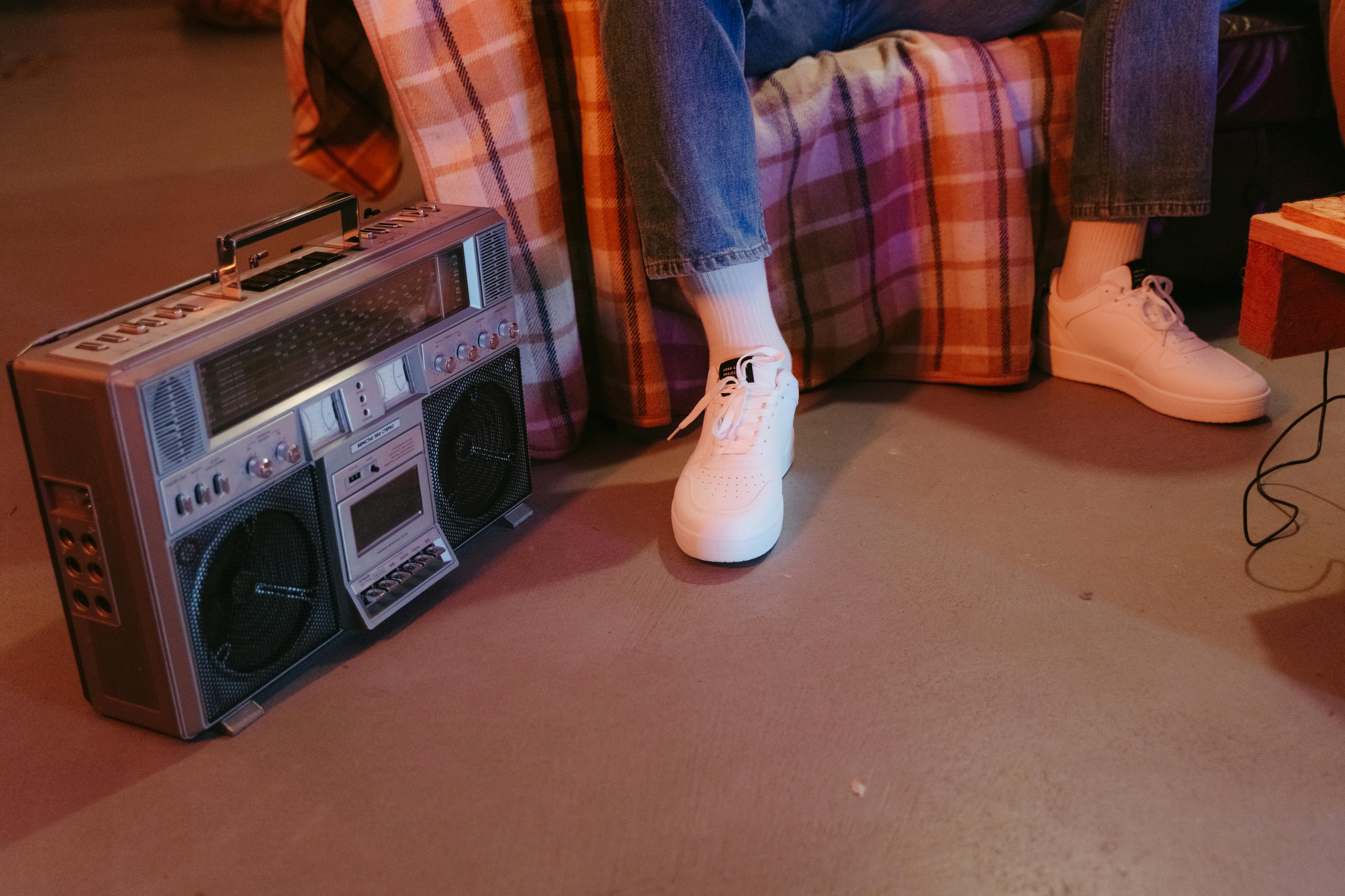 Close-up of a vintage boombox and white sneakers inside a cozy room.