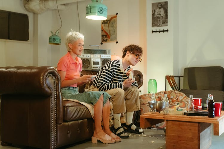 Man And Woman Sitting On Brown Sofa While Playing Video Game