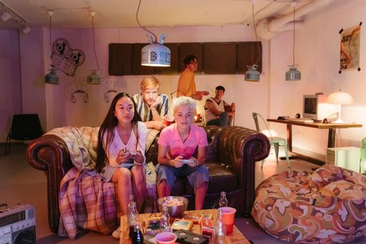 Group of friends enjoying a fun video game night indoors, sitting together on couches.