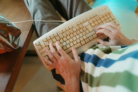 Hands typing on a retro keyboard with a vintage vibe and striped shirt casting an 80s feel.