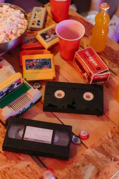 A vintage-themed table setup featuring VHS tapes, popcorn, and retro drinks.