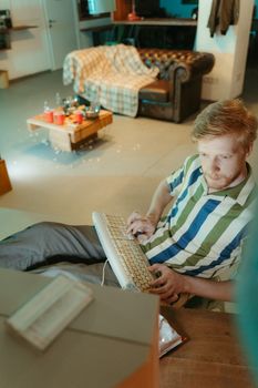Man in retro-inspired living room using vintage keyboard, casual setting.