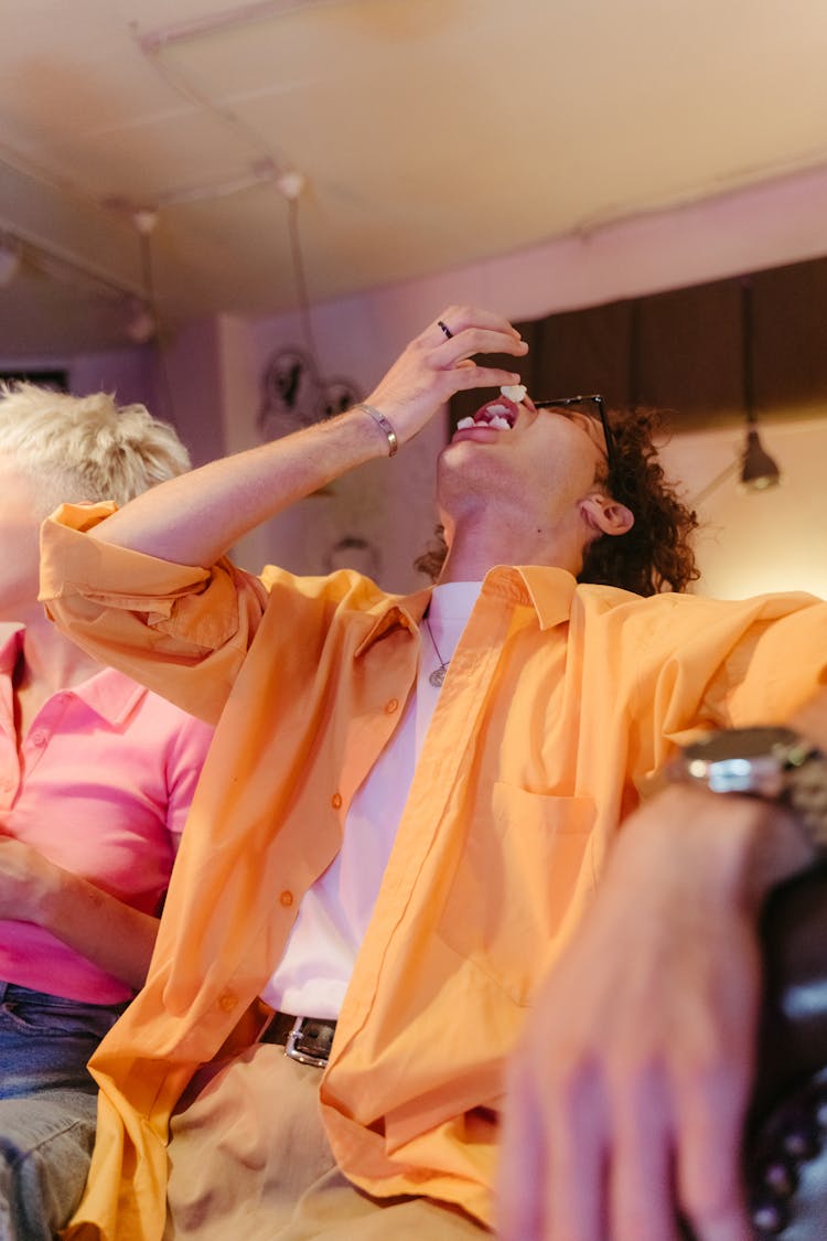 Man In Orange Shirt Eating Popcorns