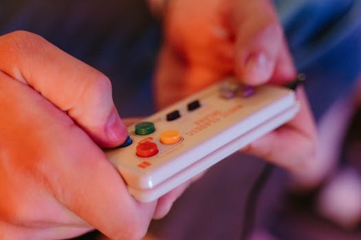 Hands holding a colorful retro game controller, evoking nostalgia for classic gaming.