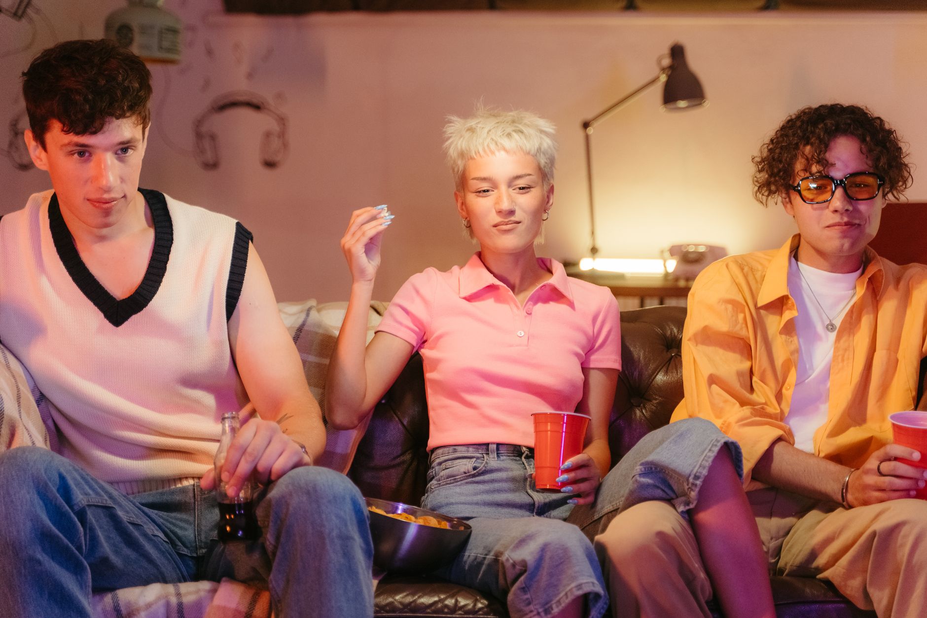 Three teenagers having fun indoors during a nostalgic movie night with snacks.