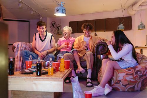 Free A joyful group of friends laughing and enjoying drinks in an indoor setting. Stock Photo