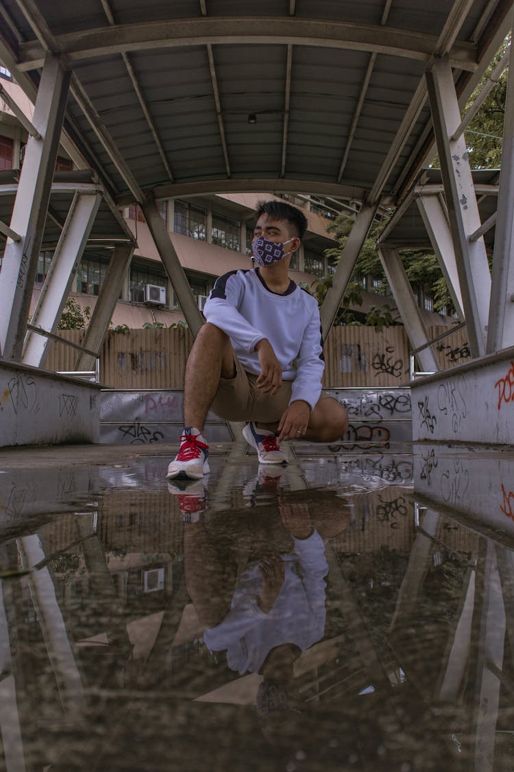 Low Angle Shot Of A Man Crouching In A Flooded Structure