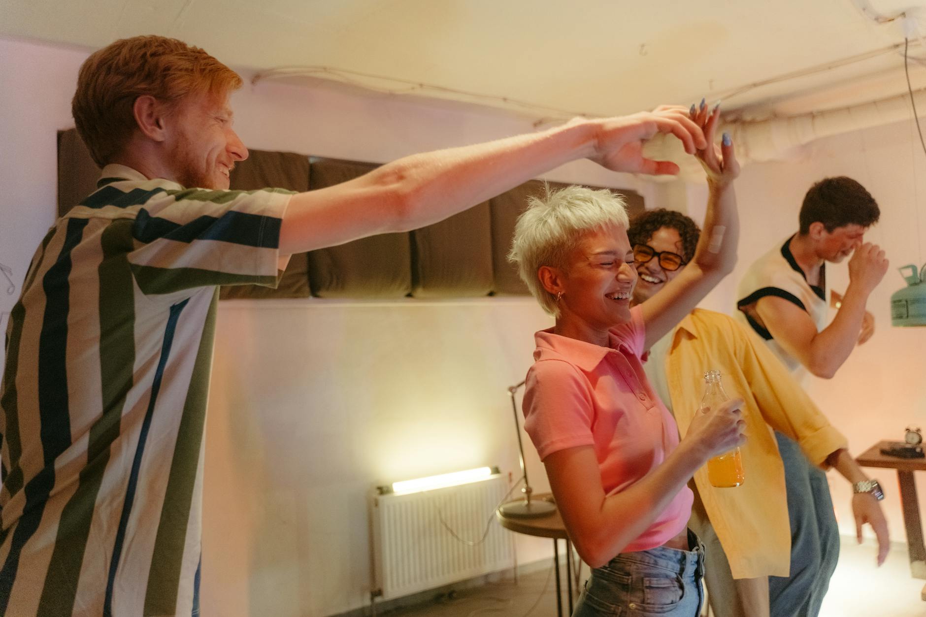 Arkadaş grubu içerisinde neşeyle gülen, sosyal ve enerjik bir kişinin odak noktası olduğu eğlenceli bir sosyal ortam.