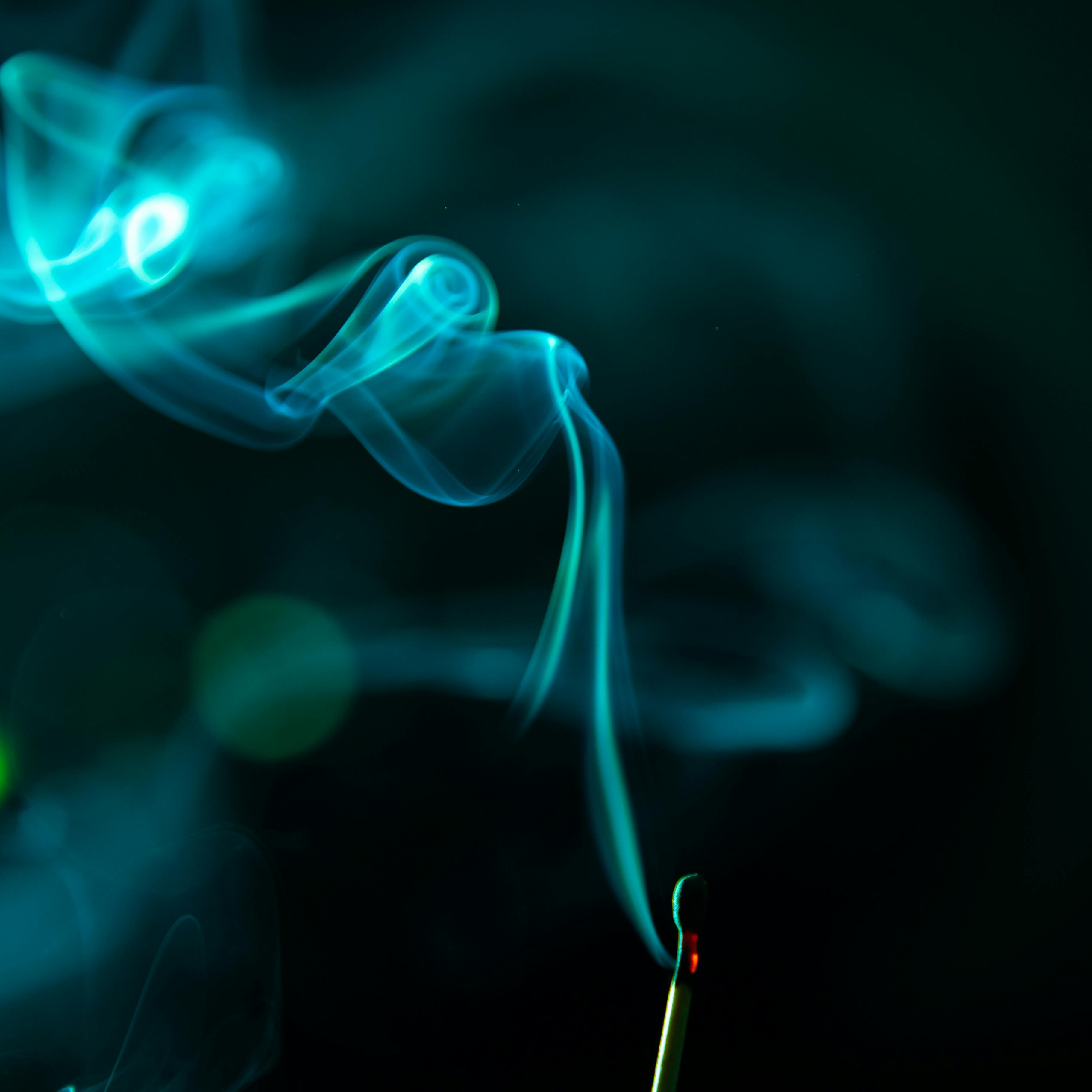 A captivating close-up of smoke swirling from a lit match stick against a dark backdrop.