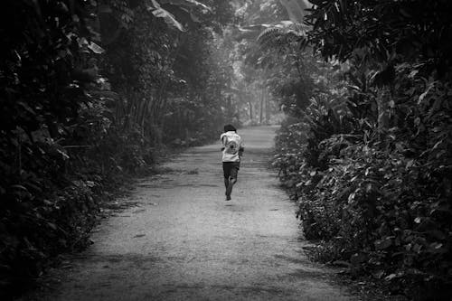 Free Grayscale Photo of a Person Running on the Dirt Road Stock Photo