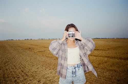 Photo of a Woman Using a Camera on a Field