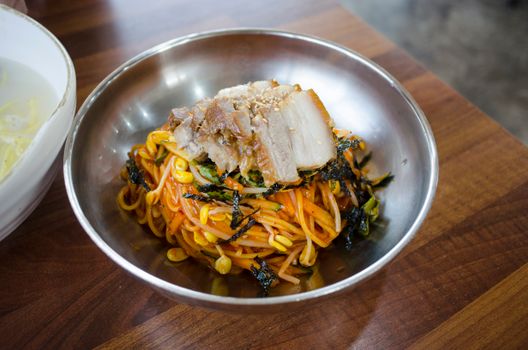 Close-up of spicy pork noodles with bean sprouts and seaweed, capturing the vibrant colors and textures.