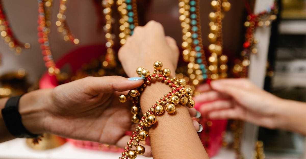 Hands trying on colorful custom jewelry with golden beads and red accents, reflecting personal style and craftsmanship for thoughtful gifting.