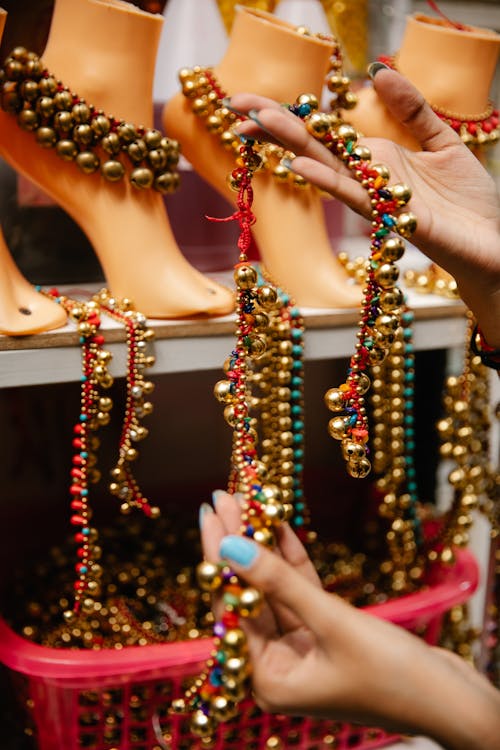 A Person Holding Gold and Red Beaded Anklet