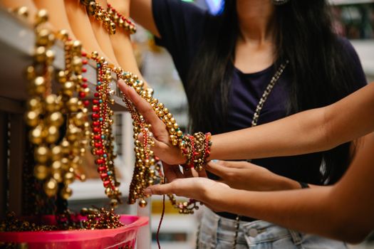 Close-up of women selecting vibrant beaded necklaces at a market stall.