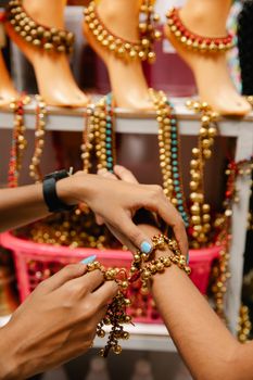 Hands trying on vibrant beaded jewelry at an indoor market stall. - Fotografer Sidoarjo