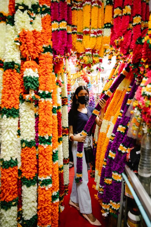 Free A woman browses colorful floral garlands in an indoor market, showcasing cultural vibrancy. Stock Photo
