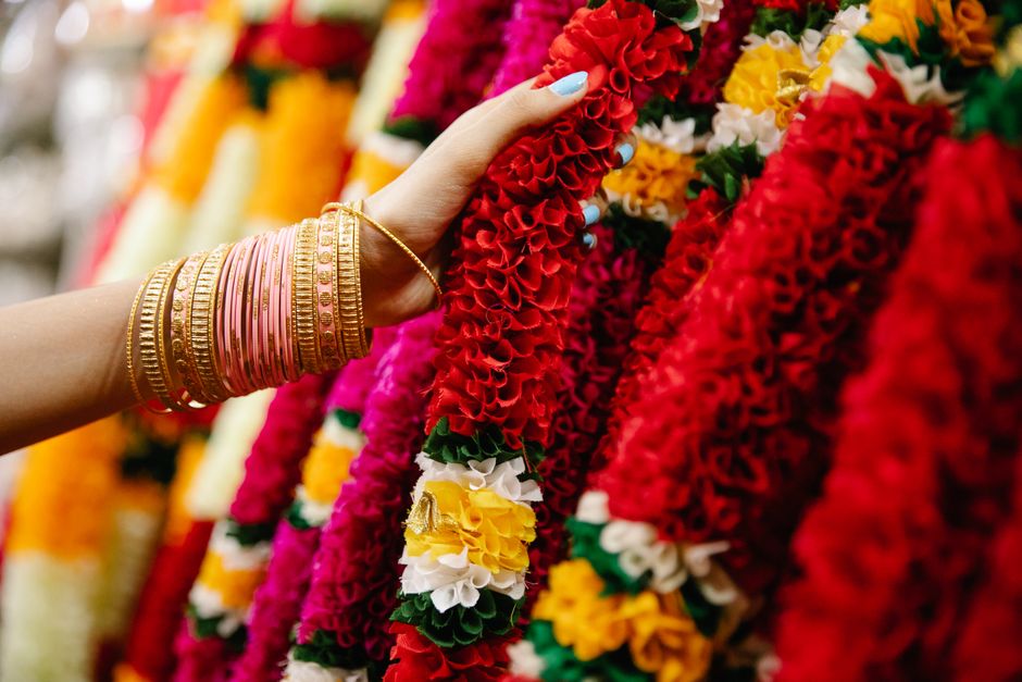 Vibrant flower garlands held by a bangled hand, symbolizing Indian culture.