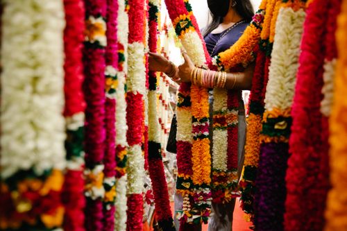 Free A person in a mask exploring vibrant garlands in a market, showcasing cultural richness. Stock Photo
