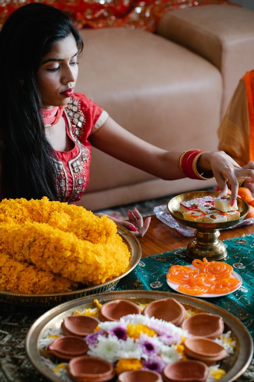 Free Indian woman preparing for a cultural celebration with flowers and traditional sweets. Stock Photo