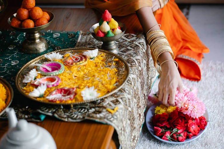 Women In Traditional Clothing Decorating The Table With Flowers 