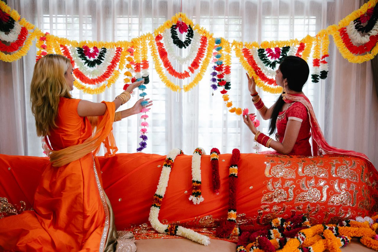 two women in traditional attire decorating a room with colorful floral