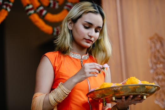 Young Indian woman in traditional attire holding a decorative platter with flowers, celebrating a festival.