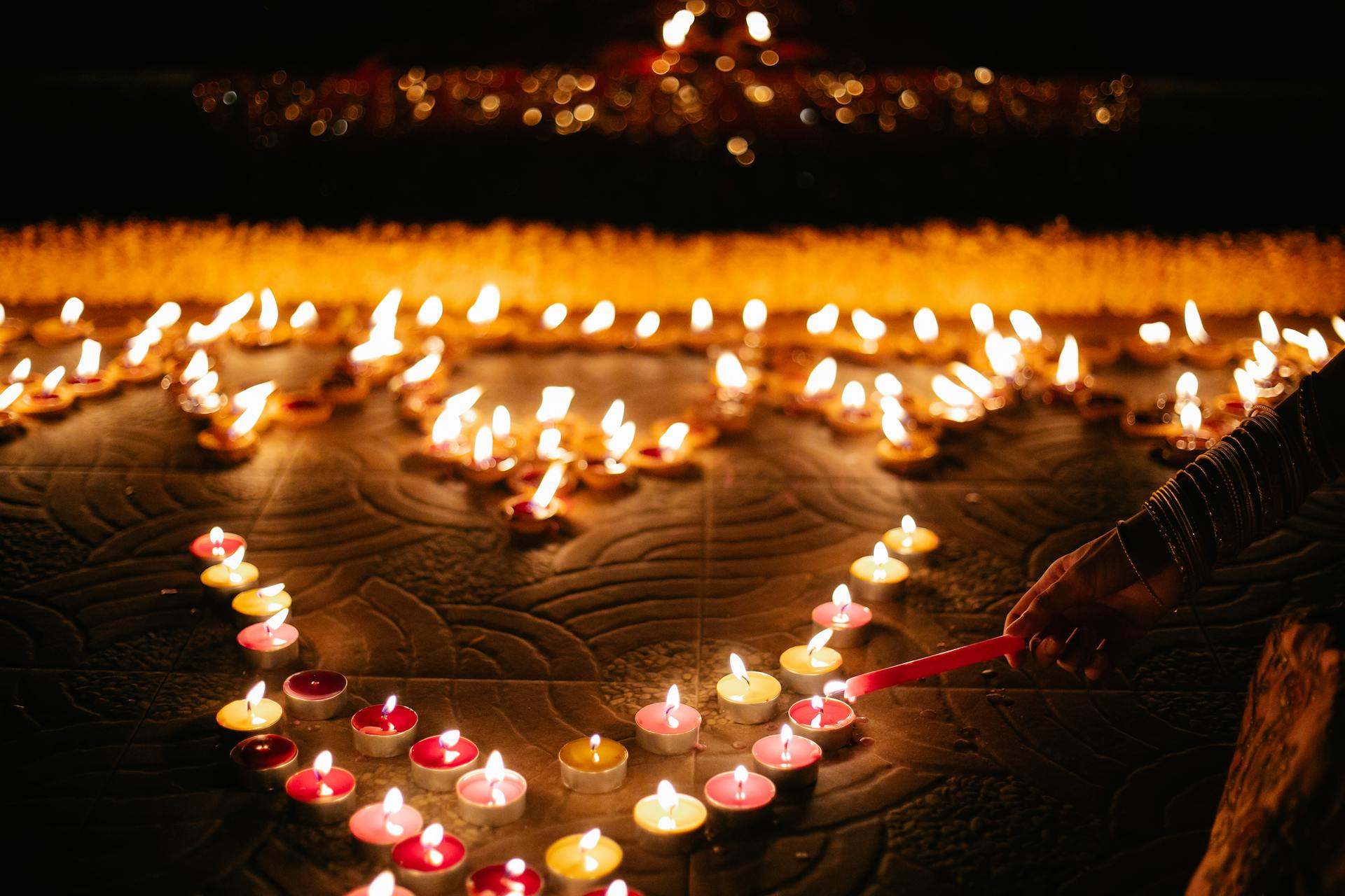 A Person Lighting a Red Candle with a Candlelight