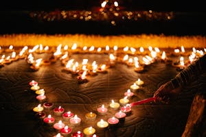 A Person Lighting a Red Candle with a Candlelight