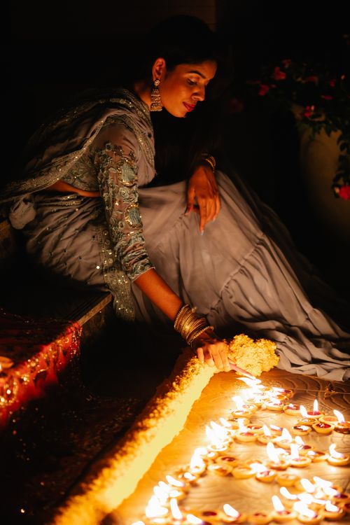 Free Woman in traditional clothing enjoying a festival with candles and floral decor at night. Stock Photo
