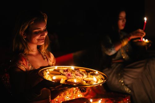 Free Two women in traditional attire performing a candle-lit Indian festival ritual at night. Stock Photo